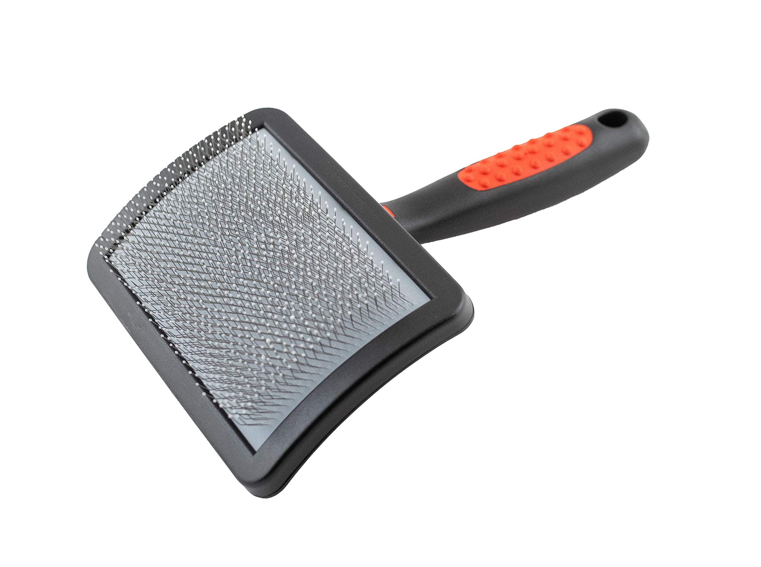A small poodle standing on a grooming table while a person gently brushes the coat with a slicker brush